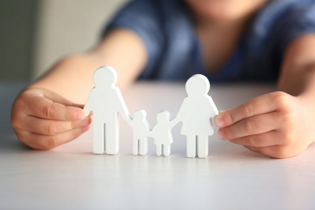 Child holding figure in shape of happy family, closeup. Adoption